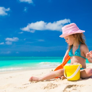 Adorable little girl playing on the beach with white sand